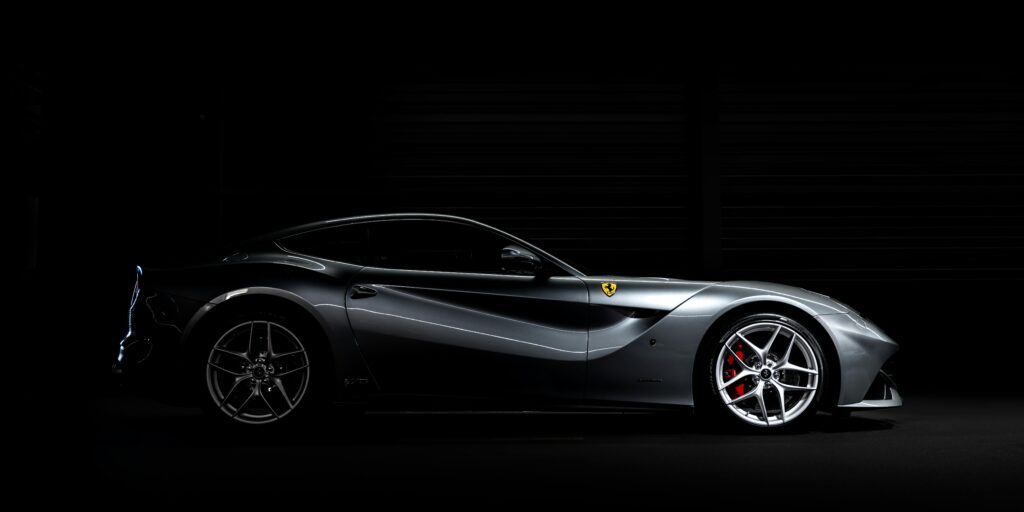 Sleek silver luxury sports car in a dark studio setting with dramatic lighting highlighting its aerodynamic profile.
