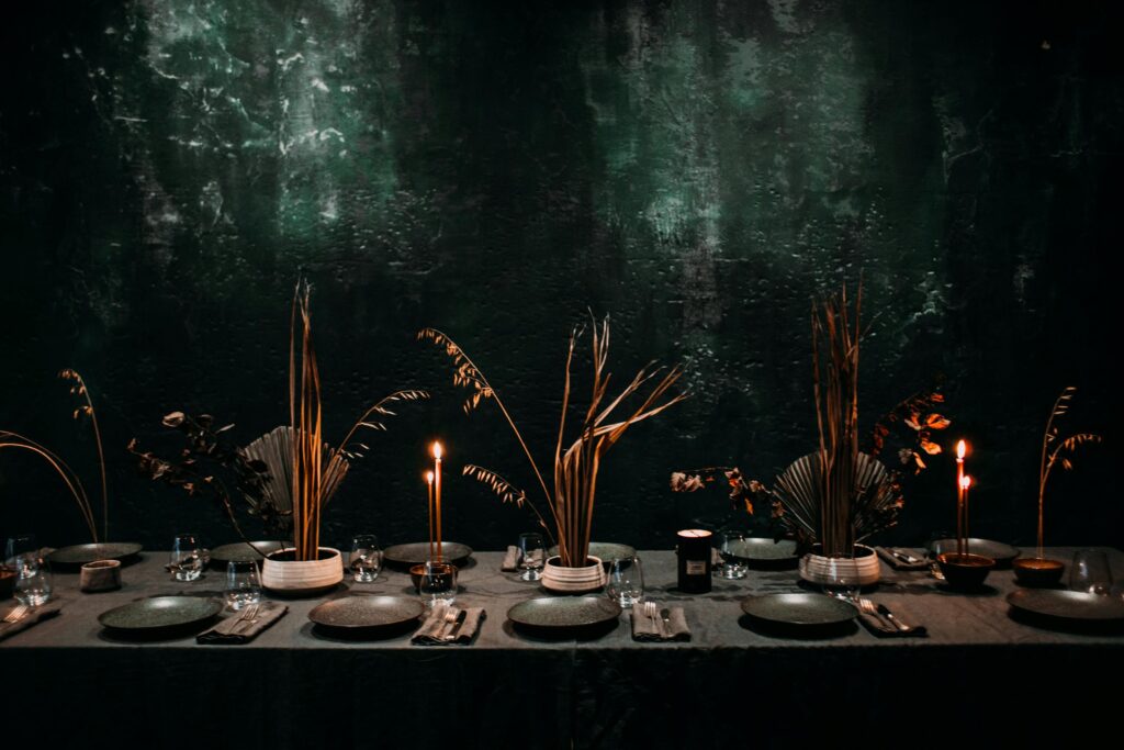 Elegant candlelit dining table with dark modern decor and refined place settings.